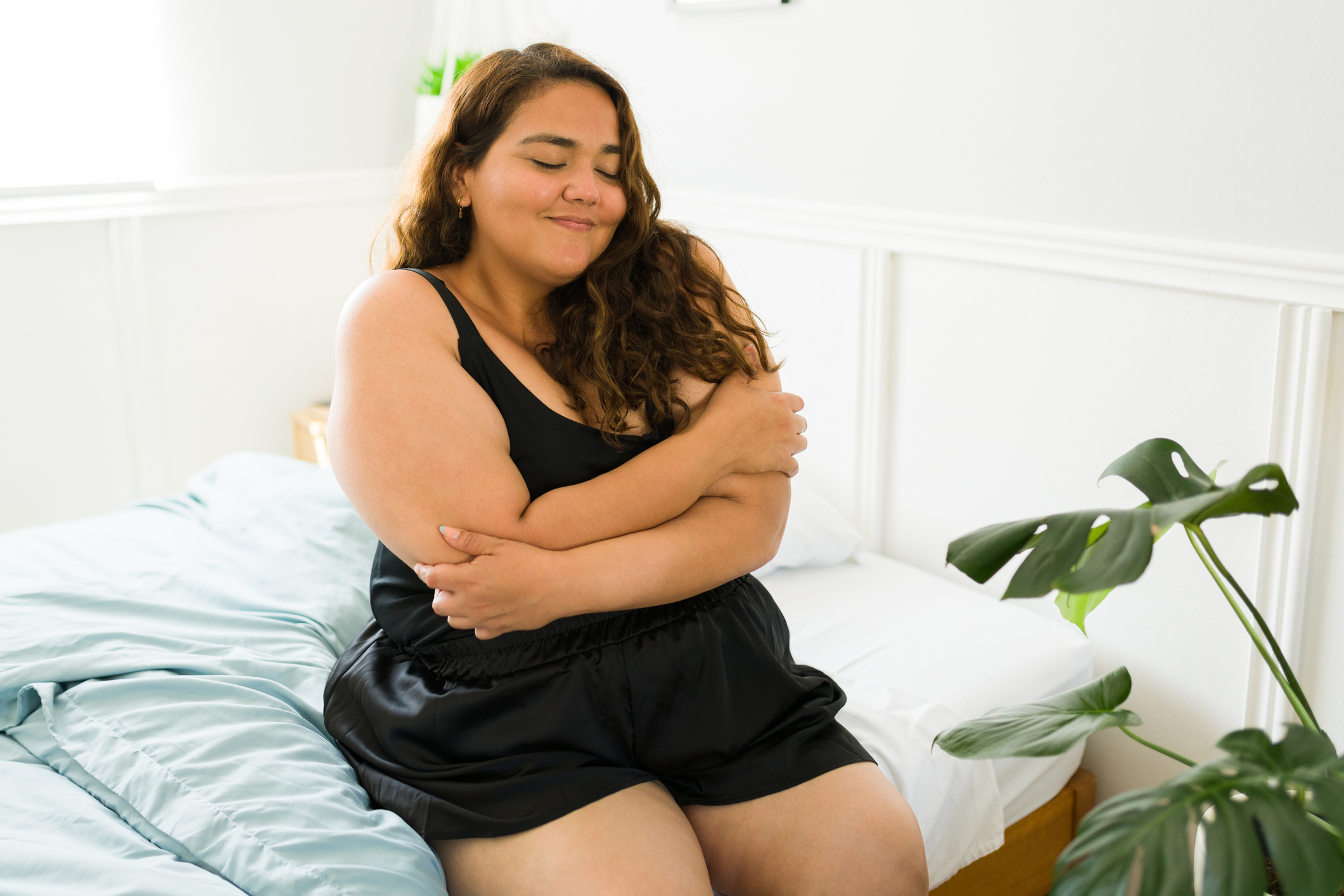Woman smiling and hugging herself in a moment of self-love and self-compassion at home