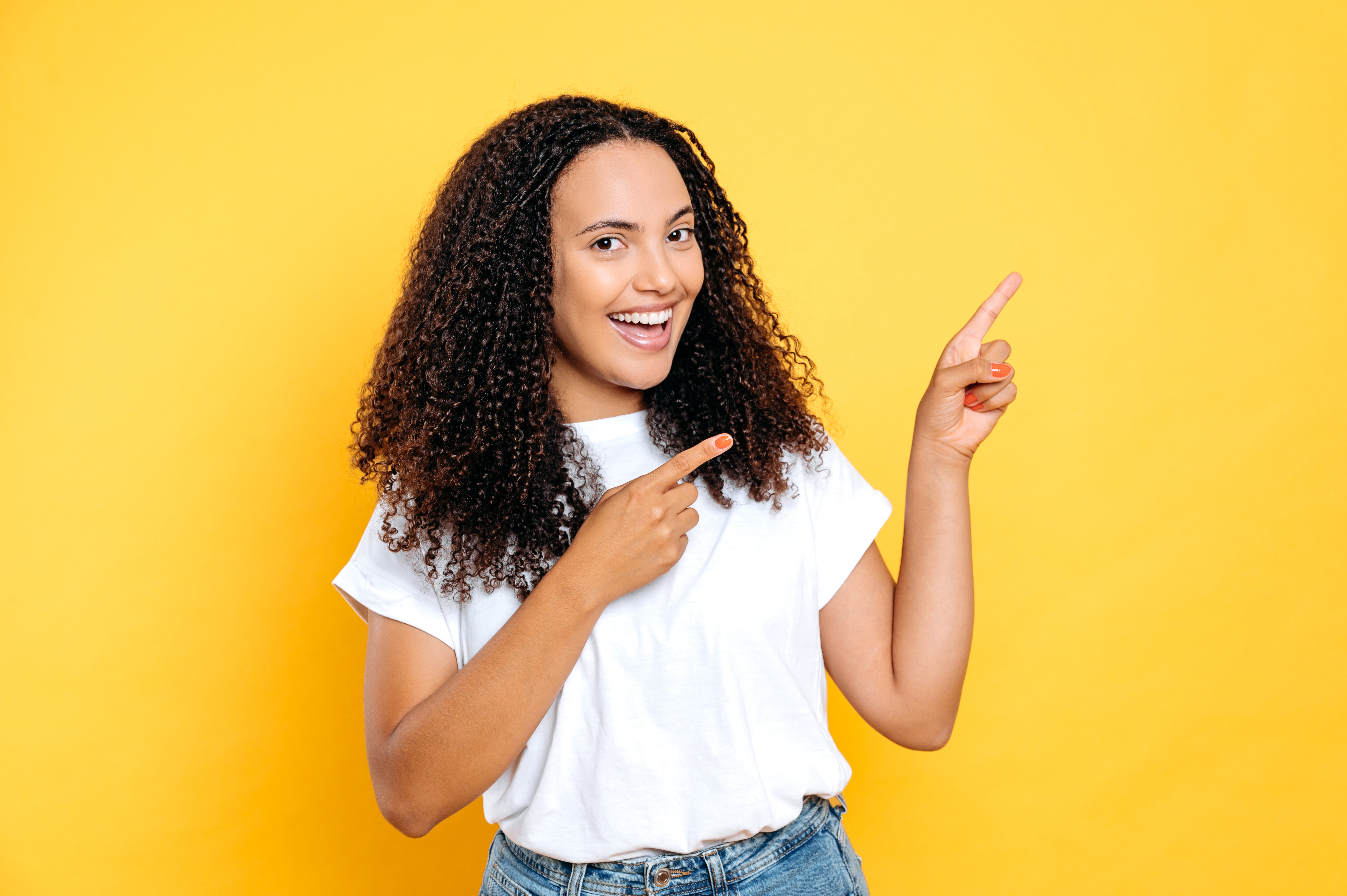 Joyful woman with curly hair smiling confidently, embracing self-expression