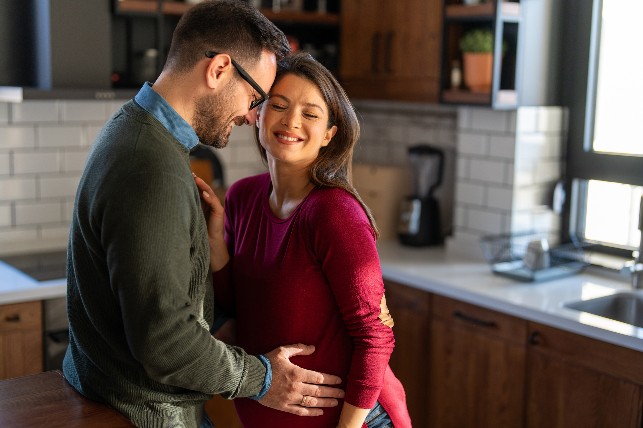 Man lovingly embraces his pregnant partner at home